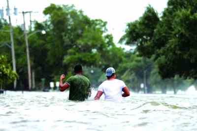 7月13日，在路易斯安那州曼德维尔，人们在被水淹没的街道上前行。